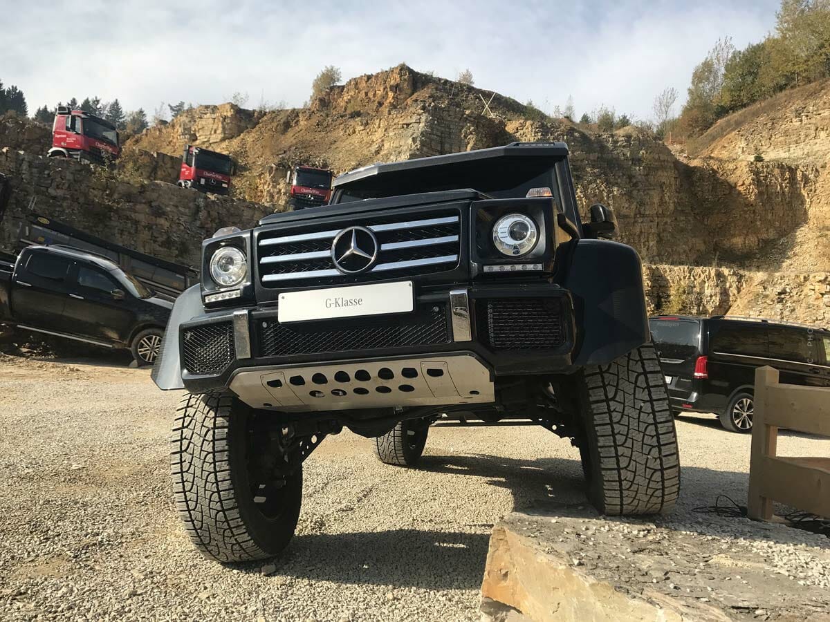 En sort firhjulstrækker står med et dæk på en sten i et sandet miljø.