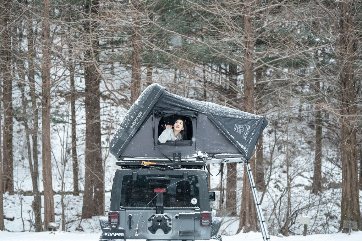 Kvinde nyder sneen omkring sit Skycamp tagtelt om vinteren