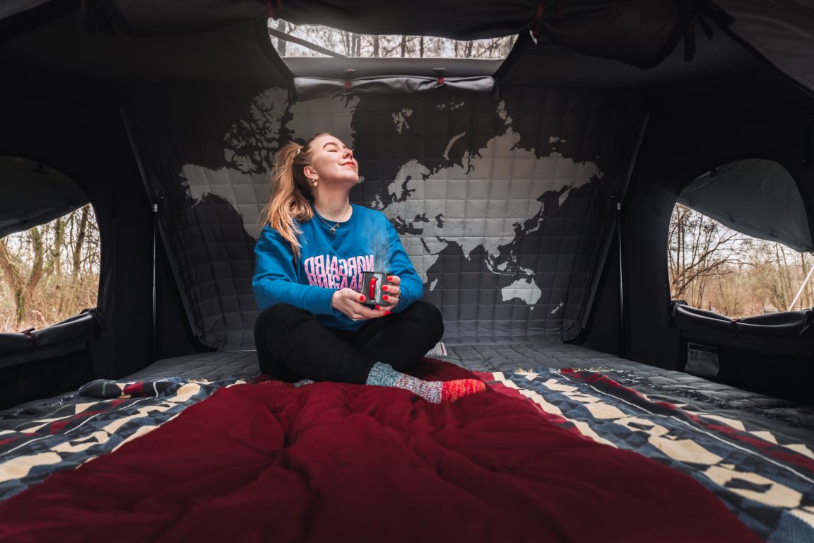 Kvinde slapper af med en kop te i sit Toyota Hilux tagtelt