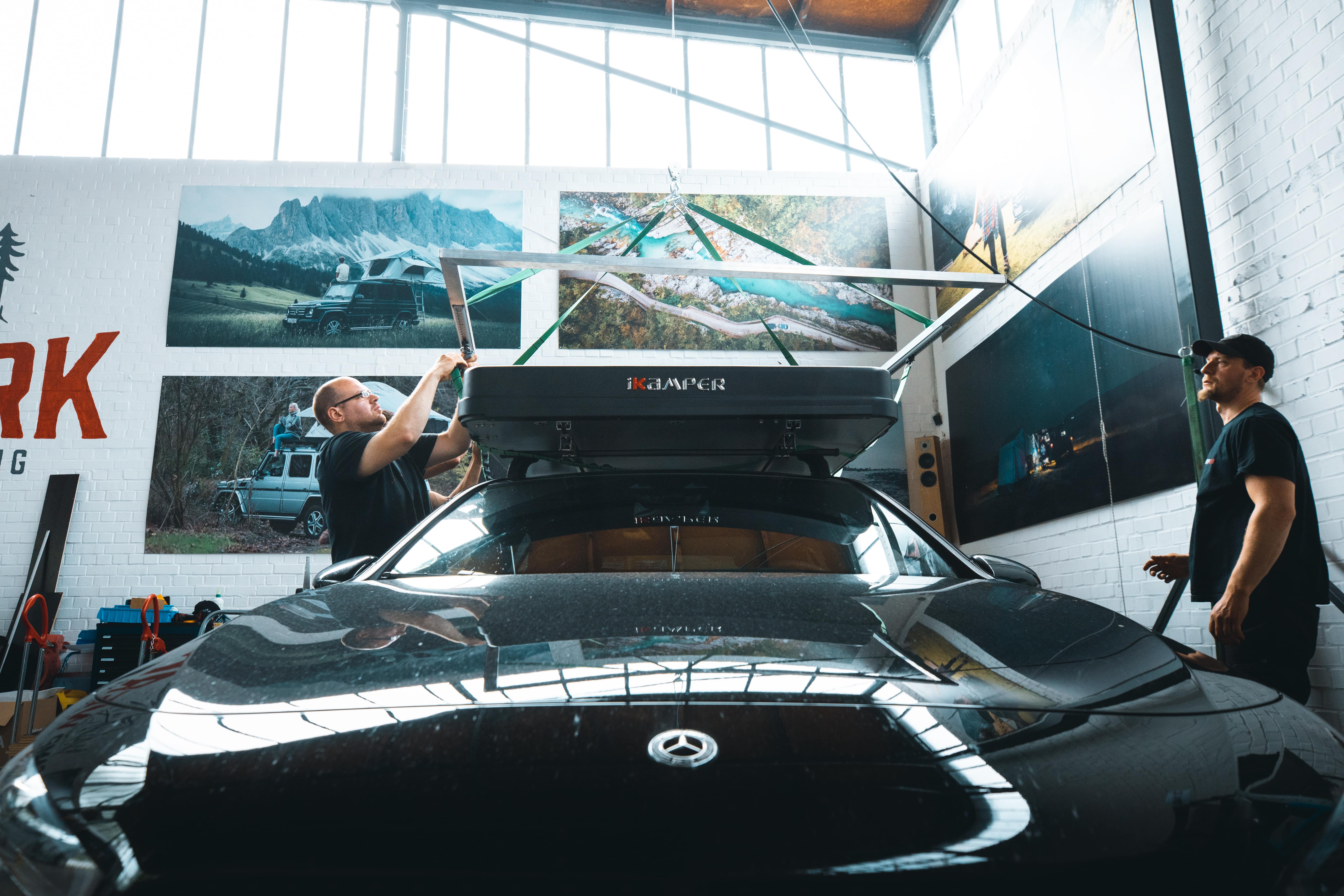Medarbejdere fra CAMPWERK monterer et tagtelt på en sort bil