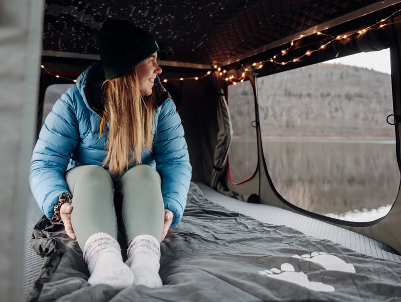 Camper sidder på et varmetæppe i sit tagtelt om vinteren